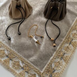 Pochons Rosa Plume pour pendule ou pierres de couleur beige posé sur une tapis de cartomancie